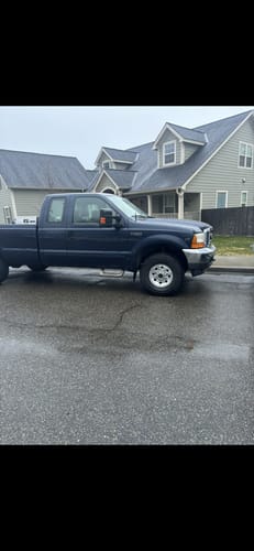 Customer's dark blue Ford F-250 truck with clean wheels after using Absolute Acid, parked on a wet street.