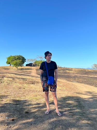Reviewer standing outdoors on a sunny day wearing the blue Nike Heritage Crossbody Bag.