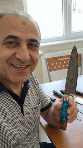 Ein Kunde zeigt ein Küchenmesser aus der Mystery Box, das eine Damastklinge und einen blauen Griff hat.