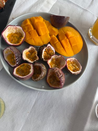 Ein Kunde zeigt die halbierten Passionsfrüchte und gewürfelte Mango auf einem Teller.