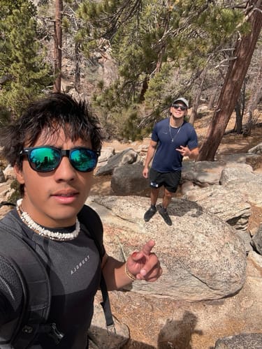 Customer taking a selfie in the dark Apex Compression Tee while hiking on a rocky trail.