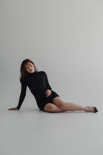 Reviewer posing in the black, long-sleeve Naked Mock Neck Mini Dress in a studio.