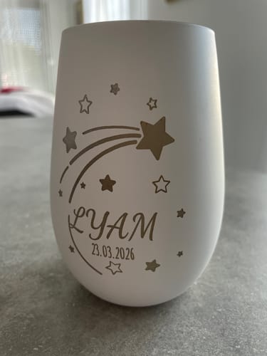Personalisierter Gedenk-Kerzenhalter eines Kunden in Weiß, mit goldener Gravur einer Sternschnuppe, Name und Datum.