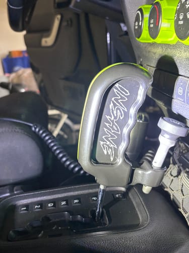 Customer's custom Hill Killer Shifter installed in a Jeep. The gray handle is engraved with 'INSANE' and has a yellow trim.