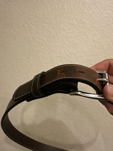 A reviewer holds the buckle end of their dark brown Wyoming Bison Lined belt, showing the contrast stitching.