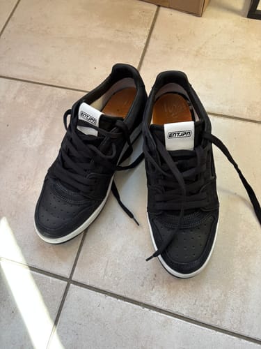 Customer's black Enterprise Japan Egg Rocket Sneakers with white soles, shown on a tiled floor.