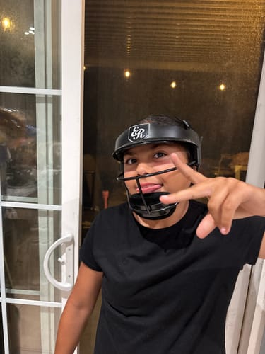 Customer playfully posing indoors while wearing the black NEO Softball Fielder's Mask.