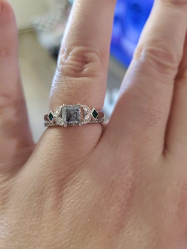 A reviewer's hand showing their sparkly engagement ring setting sitting flush against a wedding band.