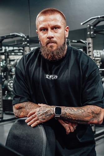 Reviewer in a gym wearing the black ASCEND HEAVY OVERSIZED TEE, showing its relaxed fit.