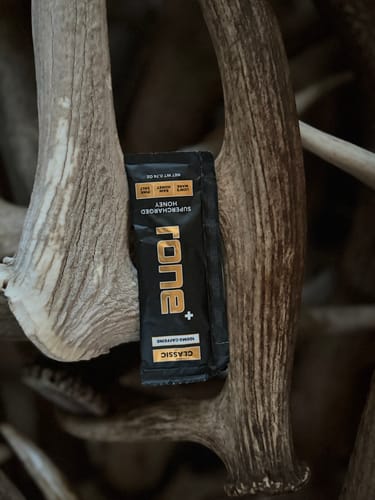 Customer's black packet of SuperCharged Honey Classic nestled amongst large, light-colored antlers.