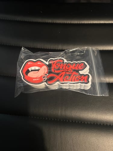 Customer's stack of custom Cut to Shape Stickers in a bag. The red design features lips, fangs, and the text 'Tongue Action'.