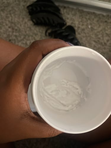 Reviewer holding an open container of QUENCHED Hydrating Buttercream, showing the creamy white product inside.