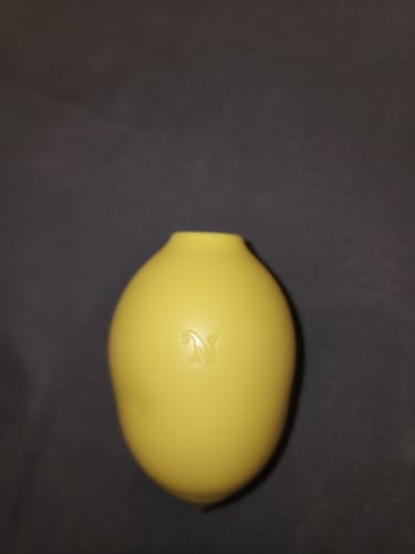 Reviewer's yellow Lem Clitoral Massager shown from above on a dark surface.