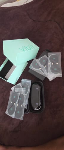 Customer's unboxed Vibit TENS device, showing the packaging, black carrying case, and multiple electrode pads.