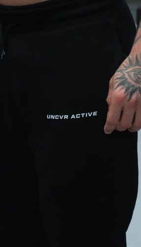 Close-up of a reviewer's black Legacy Sweat Pants, showing the logo and pocket detail.