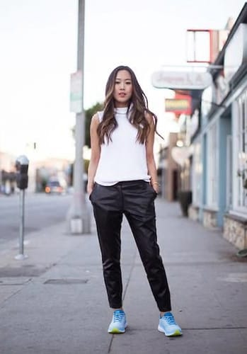 Reviewer standing on a sidewalk wearing light blue Ortho Walk shoes with black pants.