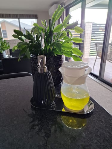 Customer's Soap Daddy dispenser with bright yellow soap sitting on a dark kitchen counter.