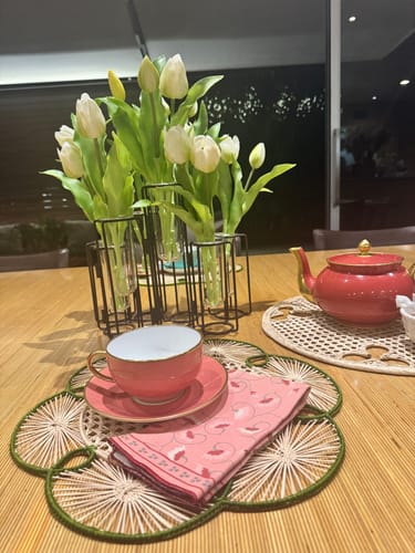 Customer's white short stem tulips in a multi-stem vase on a decorated Easter table with a teacup.