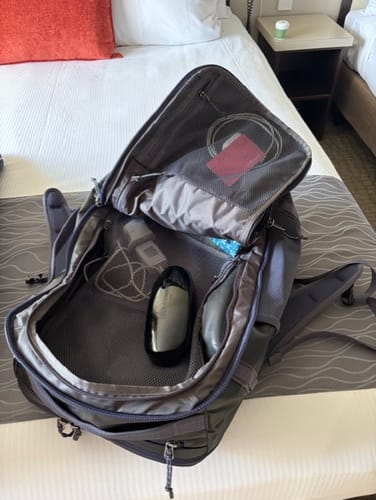 Customer's pink SPOTMINDERS Tracking Card shown inside the mesh pocket of a backpack.