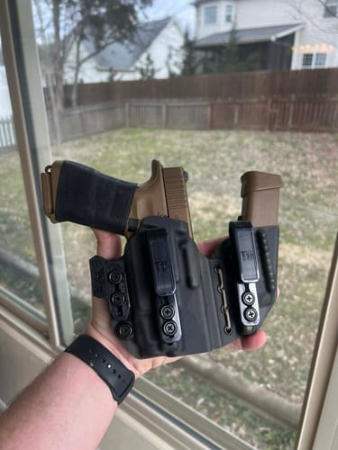 Customer holding the black AXIS ELITE holster, which contains a tan firearm with a light and a magazine.