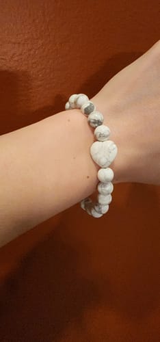 Reviewer wearing a white howlite bracelet with a heart-shaped bead on their wrist.