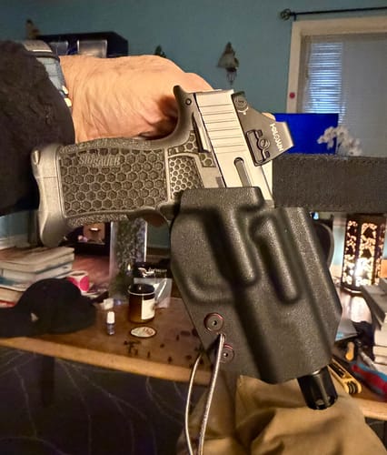 Customer's hand acquiring a full grip on their handgun, showing the fit and clearance of the OPTIO V2 holster.