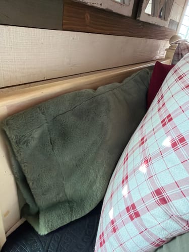 Customer's Standard Pillow Form inside a fuzzy green pillowcase, placed on a bench with other pillows.