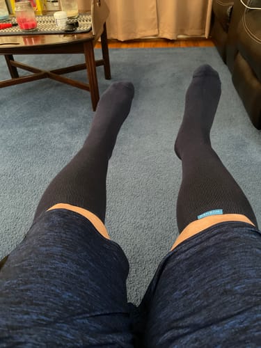 Reviewer's first-person view of their legs while wearing the dark Performance Eucalyptus Compression Socks in a living room.