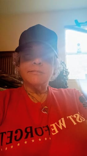Customer wearing the red 'Freedom Requires Sacrifice' t-shirt and a black cap, with their face partially shadowed.