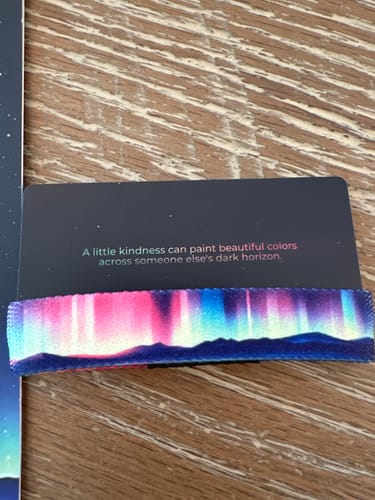 Customer's colorful Light Up The Night Bracelet with an aurora design, shown with its inspirational backing card.