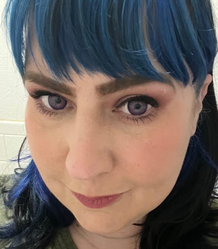 A close-up of a reviewer wearing the vibrant Vega Violet Purple contact lenses.