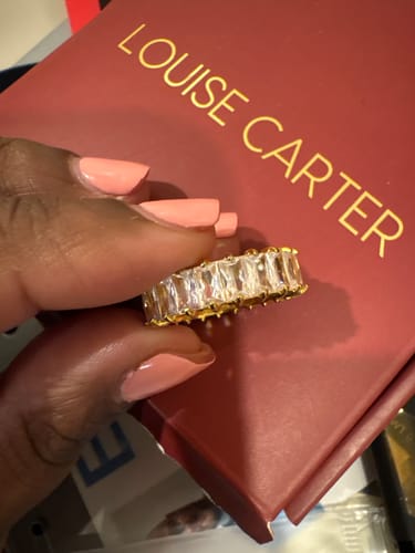Customer's hand holding the gold Chiara Eternity Ring with large, clear rectangular stones.