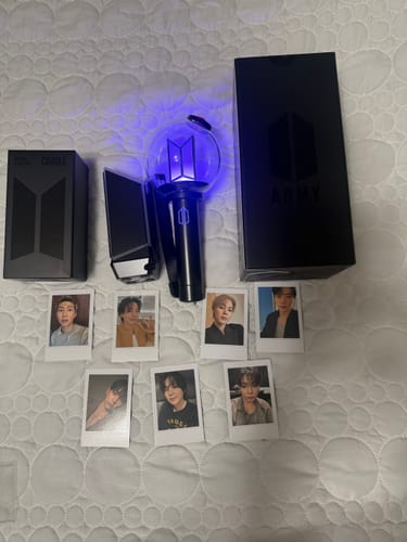 Customer's BTS Official Light Stick Ver.4 glowing blue, shown with its cradle, packaging, and seven photo cards.