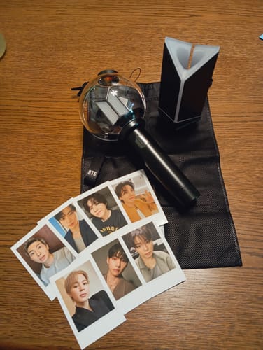 A customer's unboxed BTS Official Light Stick Ver.4, cradle, carrying pouch, and set of member photocards.