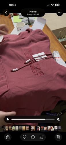 Customer's red BTS Arirang Official MD Hoodie laid on a table, showing the embroidered text and beaded drawstrings.