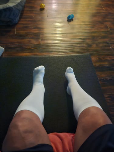 Reviewer wearing a pair of white Eucalyptus Lyocell Compression Socks while seated with legs extended.