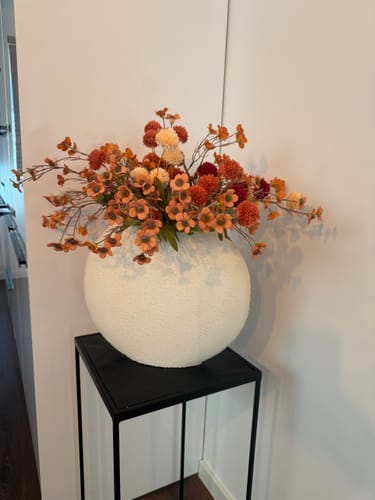 Recensent toont het Wax Arrangement in een grote, witte bolvaas op een zwarte bijzettafel.
