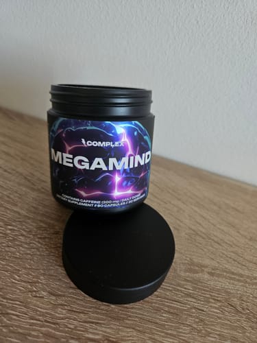 Customer's black tub of MegaMind supplement, open on a wooden table with the lid in front.