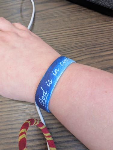 Customer's wrist with the blue 'God is in control' Bible Verse Bracelet on.