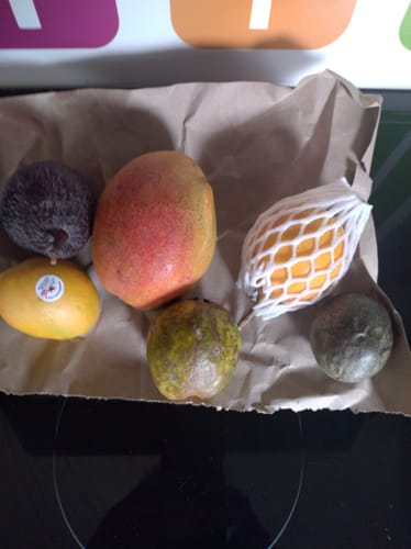 Ein Kunde zeigt eine Auswahl aus der Probierbox 'Exotische Früchte' mit Mango, Pitaya und Passionsfrucht.