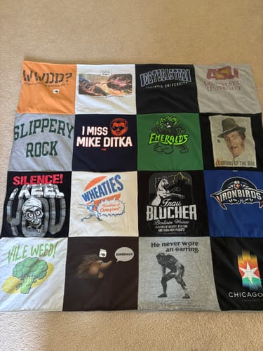 Customer's Project Repat T-Shirt Quilt, a grid of memorable graphic t-shirts, laid out on a floor.