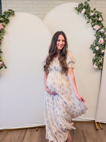 Customer wearing the floral Crinkled Chiffon Dress while pregnant and holding her baby bump.