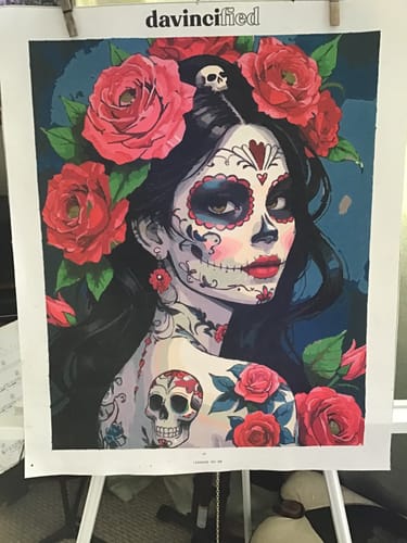 Customer's completed Day of the Dead paint by numbers kit showing a woman with skull makeup and red roses.