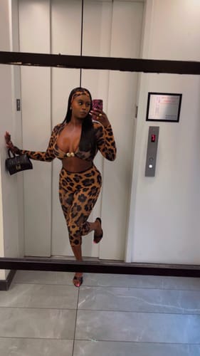 Reviewer posing in a mirror wearing the animal print Naked Print Cutout Capri Jumpsuit, showing the gold hardware.