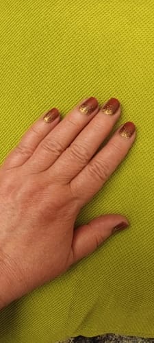 Nahaufnahme der Hand einer Rezensentin mit den roten und goldenen UV-Gel-Nagelfolien Red Velvet Gold.