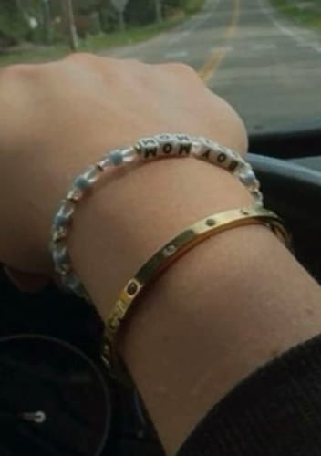 Reviewer wearing the Vina Bracelet, a gold bangle, layered with another bracelet on their wrist.
