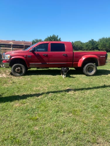 Customer's red Dodge Ram truck showing a level stance after installing the 4x4 leveling kit in a grassy field.