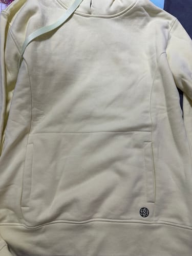 Customer's pale yellow Lemon Lime StringSwap Pullover Hoodie laid flat, showing the front kangaroo pocket and light green drawstring.