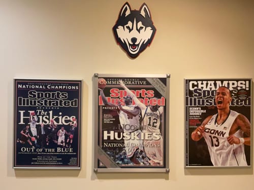 Reviewer's UCONN Huskies Mascot 3D Metal Wall Art mounted on a wall above framed UCONN memorabilia.
