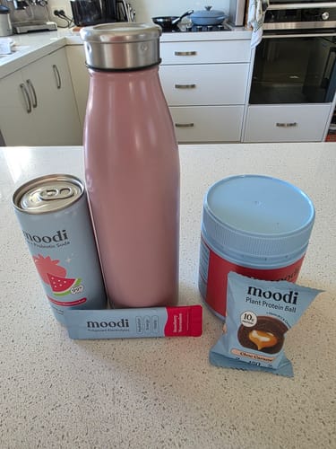Customer's Favourites Pre + Probiotic Bundle items, including a can, tub, and sachet, on a kitchen counter.